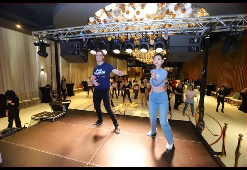 AXcent instructors leading a Bachata workshop on stage with students following behind them