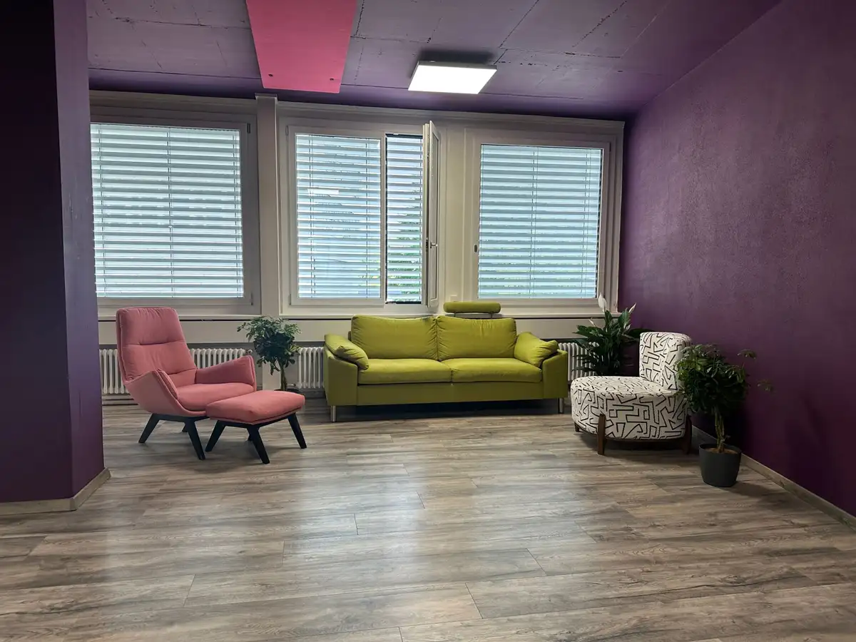 Loungebereich des Studios mit Sofas, Sesseln und violetten Wänden